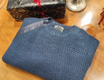 „Dunkelblauer Rusty Neal Herrenpullover aus hochwertigem Baumwoll-Mix, mit strukturiertem Strickmuster und dekorativem Reißverschluss-Detail an der Schulter, präsentiert auf einem Tisch bzw. einer Schaufensterpuppe.“