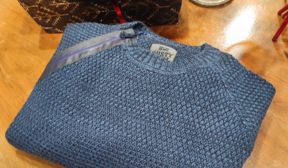 „Dunkelblauer Rusty Neal Herrenpullover aus hochwertigem Baumwoll-Mix, mit strukturiertem Strickmuster und dekorativem Reißverschluss-Detail an der Schulter, präsentiert auf einem Tisch bzw. einer Schaufensterpuppe.“