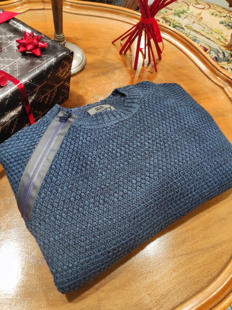 „Dunkelblauer Rusty Neal Herrenpullover aus hochwertigem Baumwoll-Mix, mit strukturiertem Strickmuster und dekorativem Reißverschluss-Detail an der Schulter, präsentiert auf einem Tisch bzw. einer Schaufensterpuppe.“