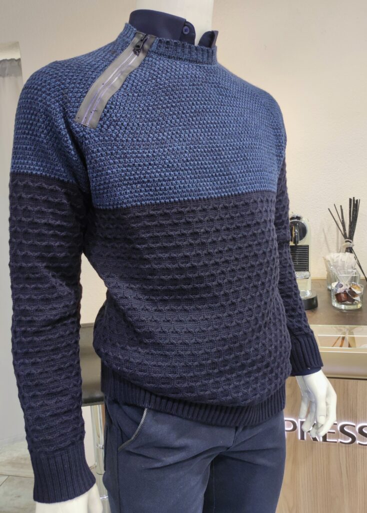„Dunkelblauer Rusty Neal Herrenpullover aus hochwertigem Baumwoll-Mix, mit strukturiertem Strickmuster und dekorativem Reißverschluss-Detail an der Schulter, präsentiert auf einem Tisch bzw. einer Schaufensterpuppe.“