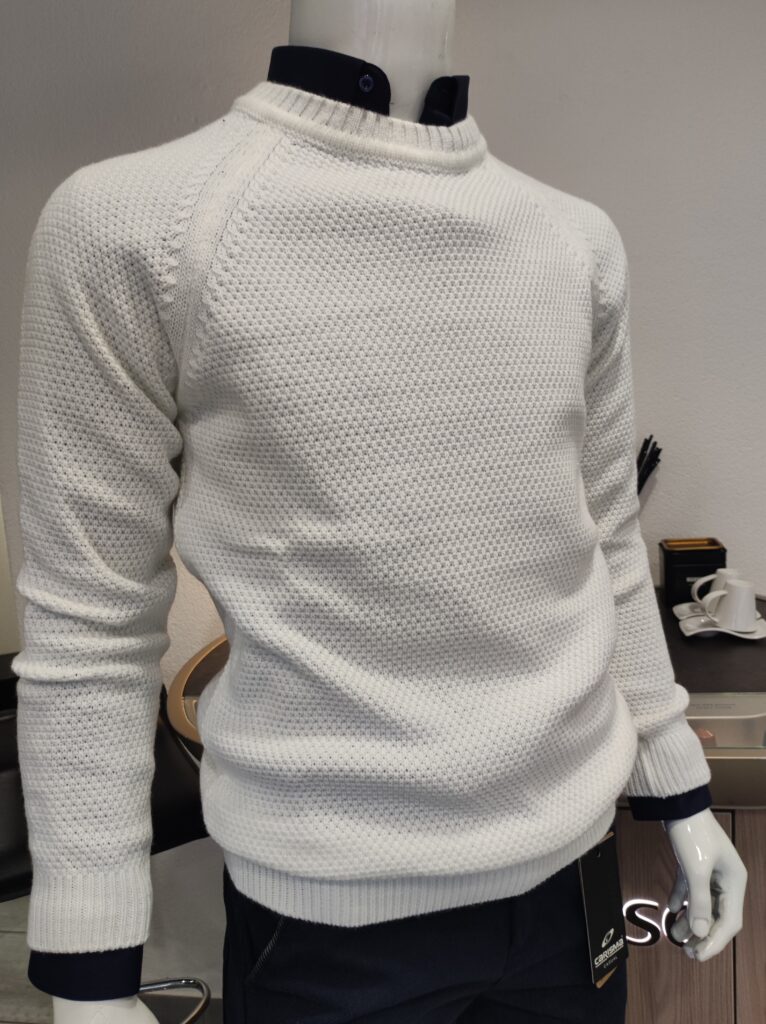 „Weißer Strickpullover auf einer Schaufensterpuppe, mit feiner Struktur und rundem Kragen, kombiniert mit dunkelblauem Hemd.“