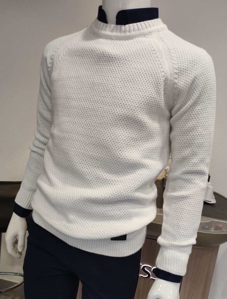 „Weißer Strickpullover auf einer Schaufensterpuppe, mit feiner Struktur und rundem Kragen, kombiniert mit dunkelblauem Hemd.“