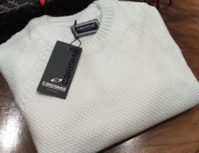 „Weißer Strickpullover auf einer Schaufensterpuppe, mit feiner Struktur und rundem Kragen, kombiniert mit dunkelblauem Hemd.“